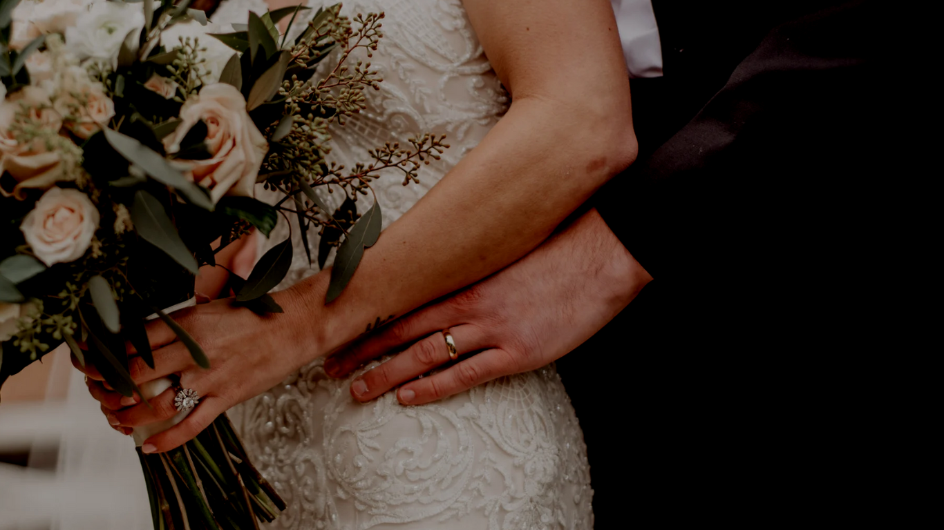 wedding photo close up, you can se man holing woman in wedding dress close up on the bouquet
